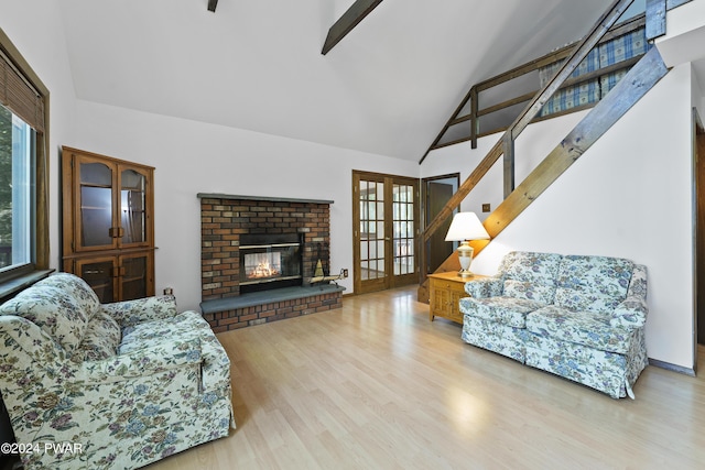 living room featuring french doors, light wood-type flooring, beam ceiling, high vaulted ceiling, and a fireplace