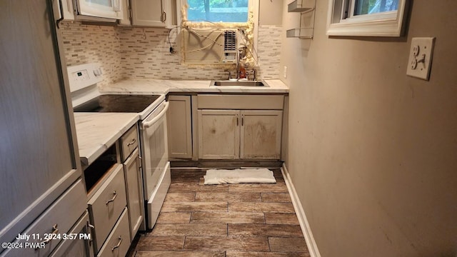 kitchen featuring electric range, decorative backsplash, light stone countertops, and sink