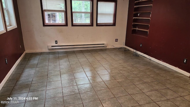 spare room featuring tile patterned flooring and a baseboard heating unit