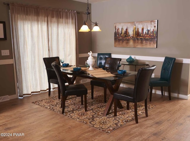 dining room featuring wood-type flooring and an inviting chandelier