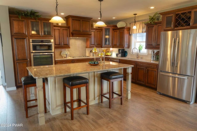 kitchen featuring decorative light fixtures, stainless steel appliances, a kitchen island, and sink