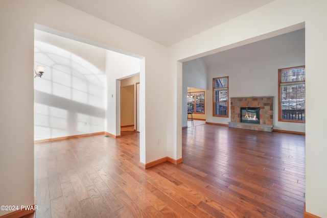 unfurnished living room featuring hardwood / wood-style floors and a stone fireplace