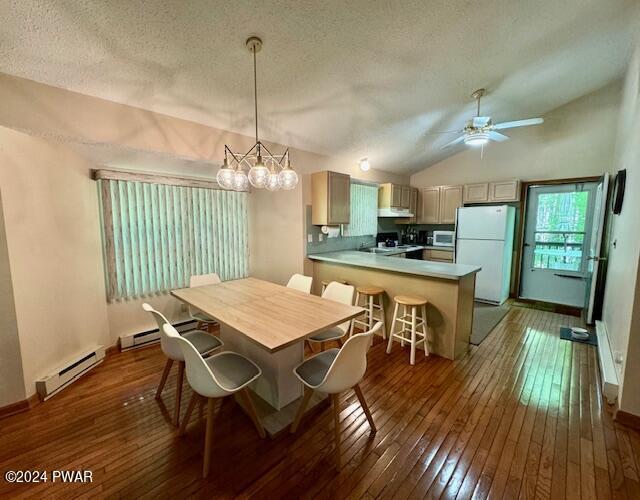 dining space featuring baseboard heating, dark hardwood / wood-style flooring, a textured ceiling, and lofted ceiling