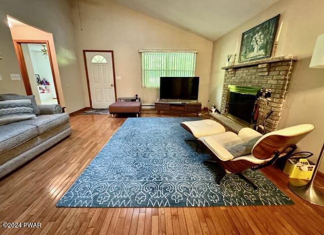 living room with ceiling fan, a baseboard radiator, a brick fireplace, high vaulted ceiling, and wood-type flooring