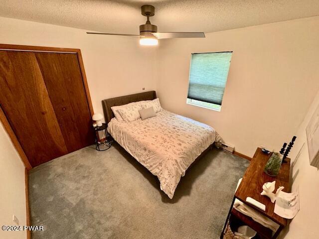 carpeted bedroom featuring ceiling fan, a textured ceiling, and a closet