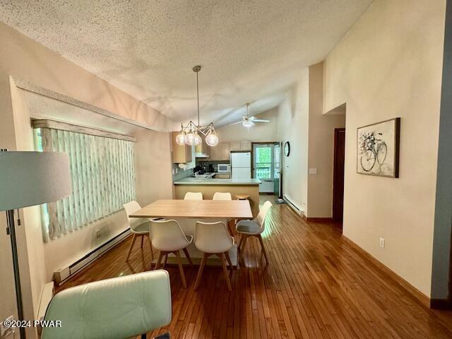 dining room featuring a textured ceiling, ceiling fan with notable chandelier, dark wood-type flooring, a baseboard radiator, and lofted ceiling