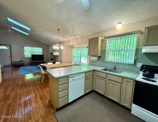 kitchen with kitchen peninsula, white appliances, ceiling fan with notable chandelier, sink, and lofted ceiling