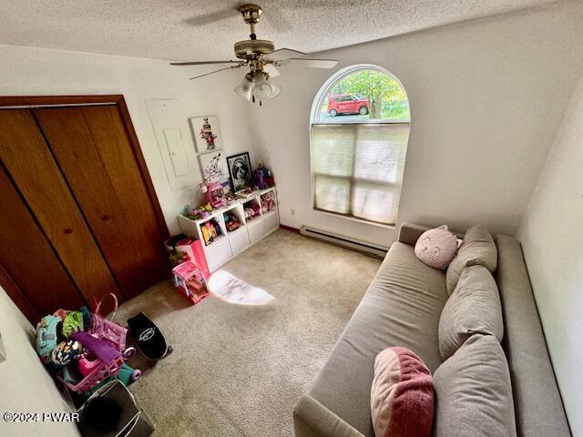 playroom with a textured ceiling, light colored carpet, ceiling fan, and a baseboard heating unit