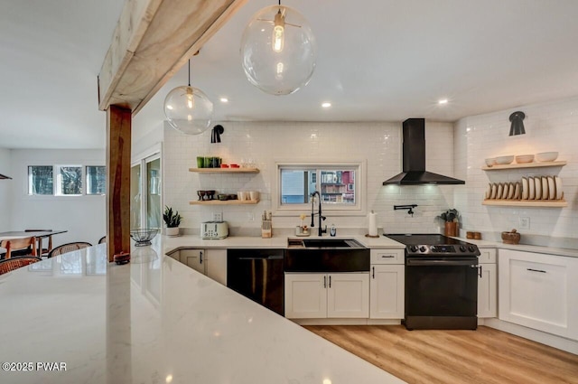 kitchen featuring wall chimney exhaust hood, sink, white cabinetry, decorative light fixtures, and black appliances