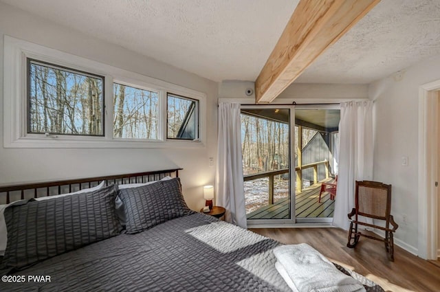 bedroom with hardwood / wood-style floors, beam ceiling, access to outside, and a textured ceiling