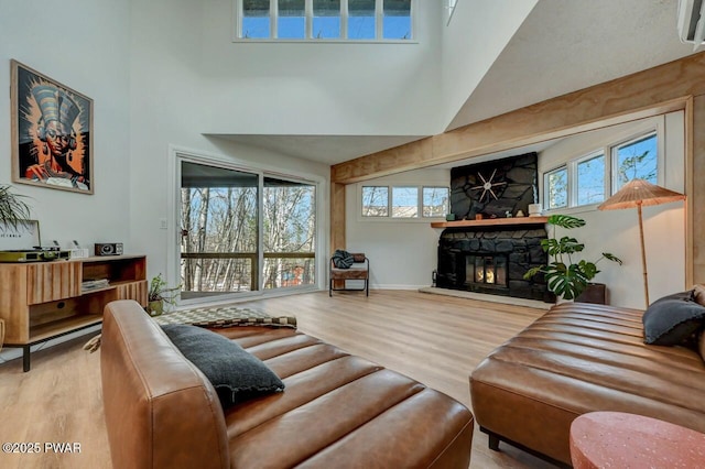 living room featuring wood-type flooring, a stone fireplace, and a wealth of natural light