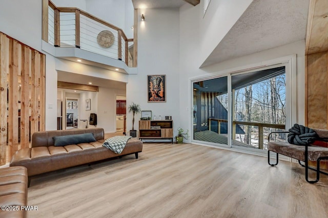 living room with a towering ceiling and light hardwood / wood-style flooring