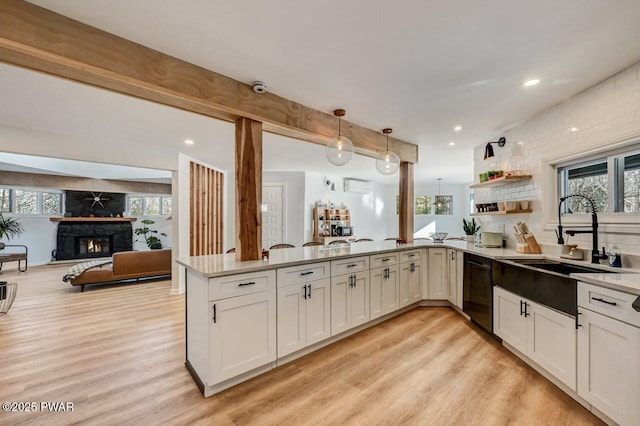 kitchen with sink, decorative light fixtures, black dishwasher, kitchen peninsula, and a fireplace