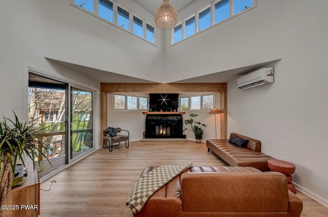 living room with hardwood / wood-style flooring, an AC wall unit, and a high ceiling