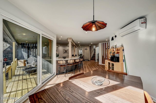 dining space featuring a wall mounted air conditioner, hardwood / wood-style flooring, and bar area