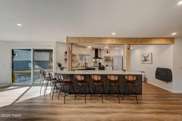 bar with wall chimney range hood, light hardwood / wood-style flooring, sink, and white refrigerator