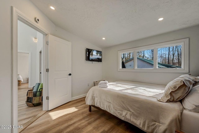 bedroom featuring hardwood / wood-style flooring, lofted ceiling, and a textured ceiling