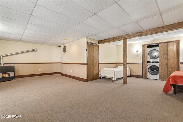 basement with stacked washer / dryer, carpet, and a drop ceiling