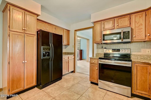 kitchen featuring backsplash, light stone countertops, light tile patterned floors, and stainless steel appliances