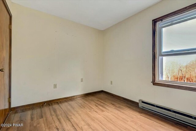 unfurnished room featuring baseboard heating and light hardwood / wood-style flooring