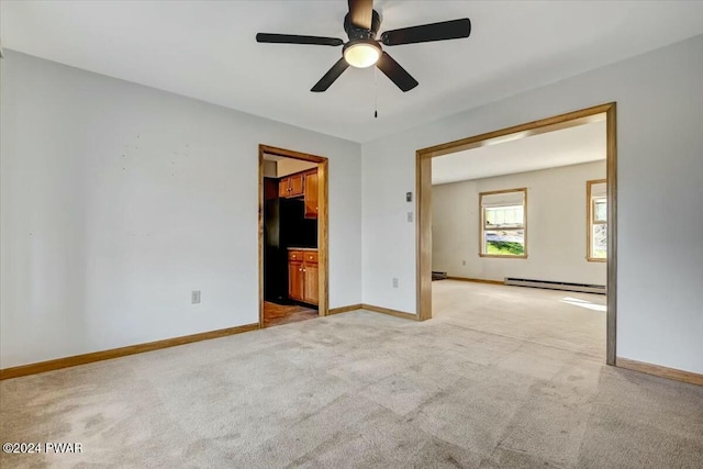 carpeted spare room featuring baseboard heating and ceiling fan