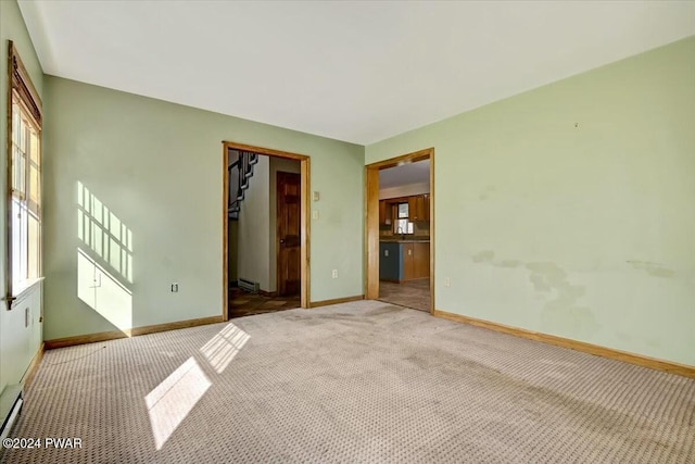 carpeted spare room with a baseboard heating unit