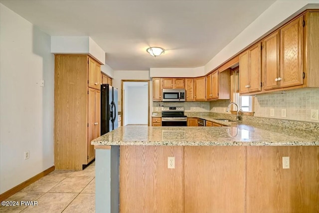 kitchen with light stone countertops, sink, kitchen peninsula, decorative backsplash, and appliances with stainless steel finishes