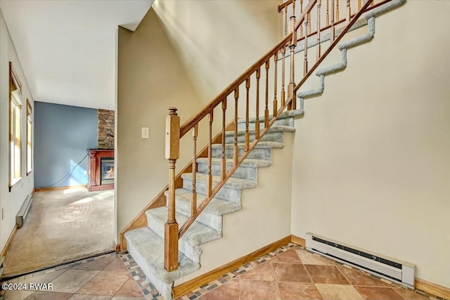 stairway featuring baseboard heating and a fireplace