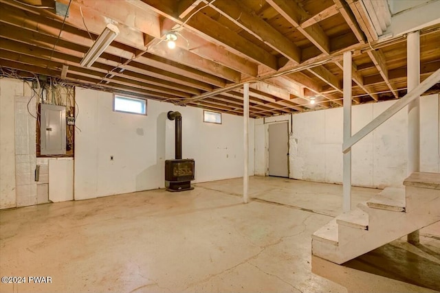 basement featuring electric panel and a wood stove