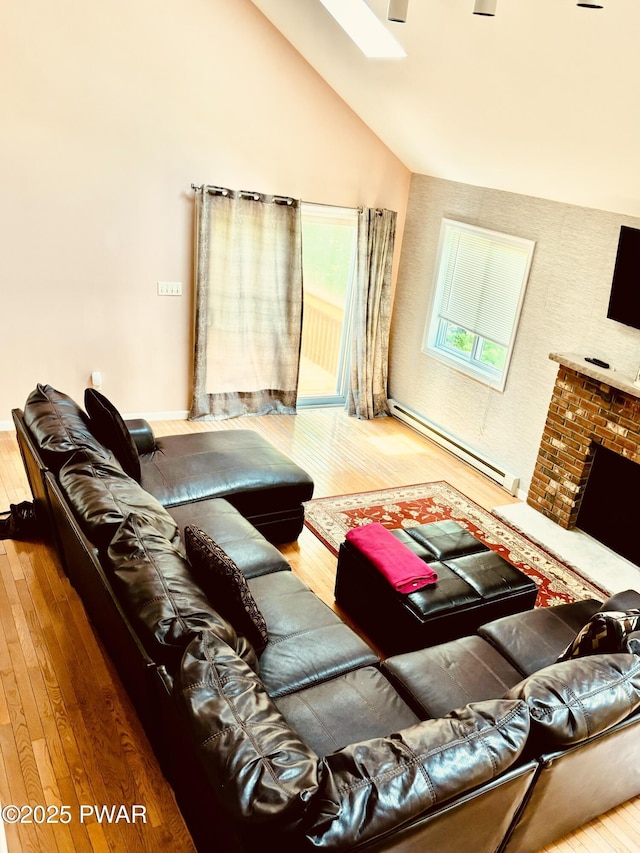 129 Skyview Rd, Dingmans Ferry, PA 18328 - living room with hardwood / wood-style flooring, a baseboard heating unit, lofted ceiling, a skylight, and a fireplace