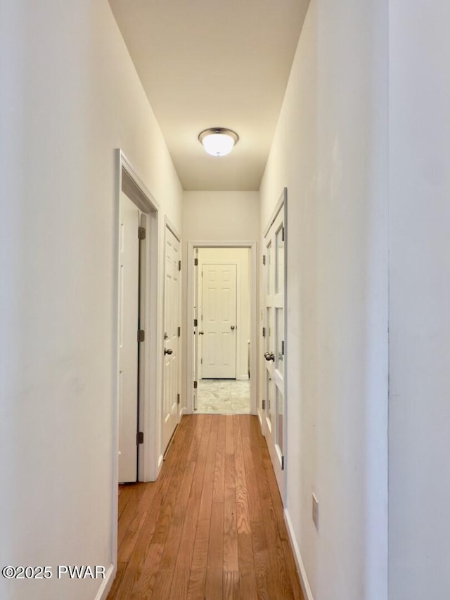 corridor featuring baseboards and hardwood / wood-style floors