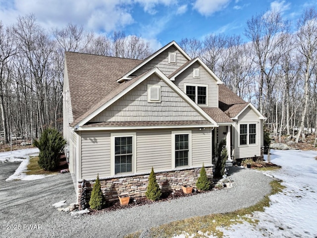 view of front of house with stone siding and roof with shingles