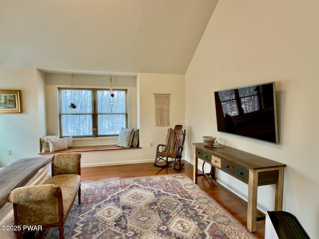 living area with lofted ceiling, baseboards, and wood finished floors