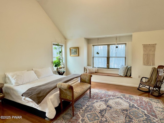 bedroom with lofted ceiling, baseboards, and wood finished floors