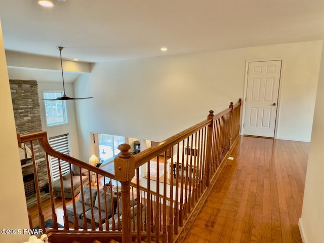 corridor with recessed lighting, a high ceiling, an upstairs landing, baseboards, and hardwood / wood-style flooring