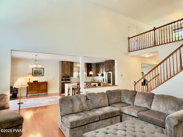 living area with a high ceiling, stairway, and light wood finished floors