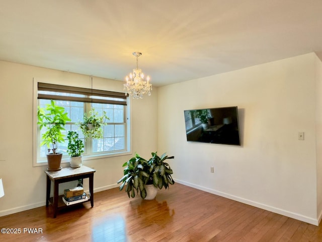 living area featuring a chandelier, wood finished floors, and baseboards