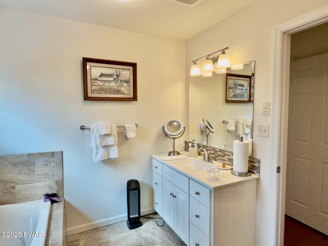 full bathroom with tiled tub, baseboards, and vanity