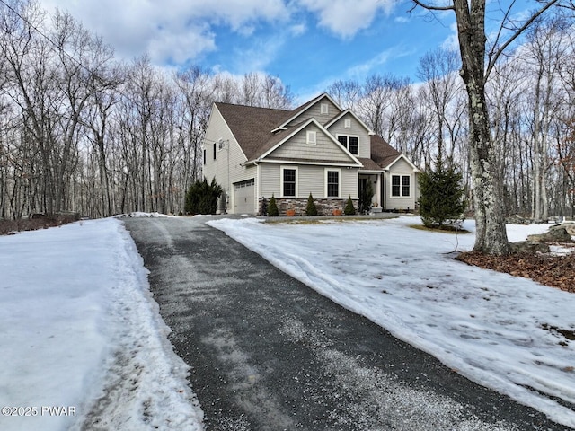 view of front of house featuring stone siding, driveway, and an attached garage