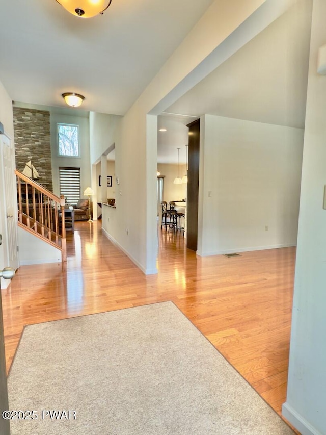 foyer entrance featuring baseboards, visible vents, stairway, and wood finished floors