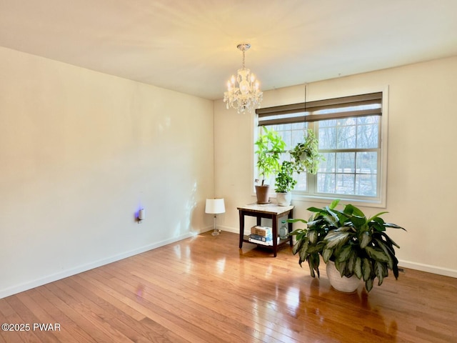 interior space with baseboards, hardwood / wood-style floors, and an inviting chandelier