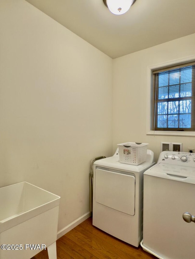 laundry area with laundry area, washer and clothes dryer, baseboards, and wood finished floors