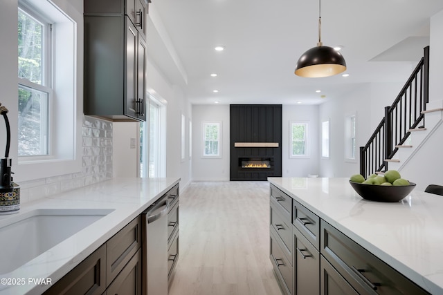 131 Song Mountain Dr, Tafton, PA 18464 - kitchen with stainless steel dishwasher, a fireplace, light wood-style flooring, light stone countertops, and decorative light fixtures