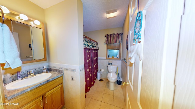 bathroom with tile patterned floors, vanity, a textured ceiling, tile walls, and toilet