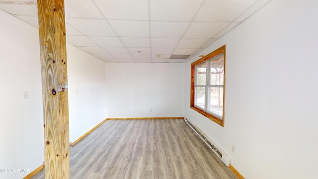 unfurnished room with a drop ceiling, light hardwood / wood-style floors, and baseboard heating