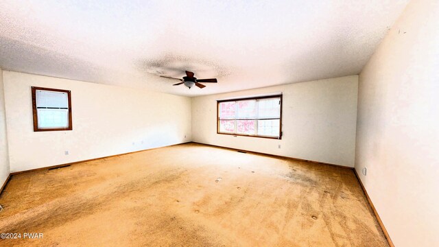 carpeted spare room featuring ceiling fan and a textured ceiling