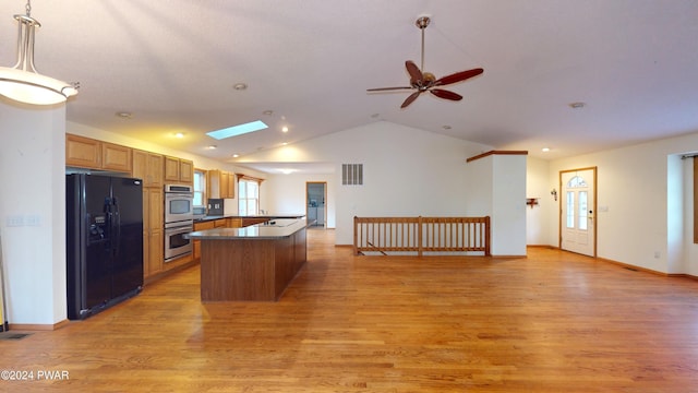 kitchen featuring ceiling fan, light wood-type flooring, decorative light fixtures, black fridge with ice dispenser, and stainless steel double oven