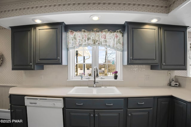 kitchen featuring light countertops, dishwasher, a sink, and wallpapered walls