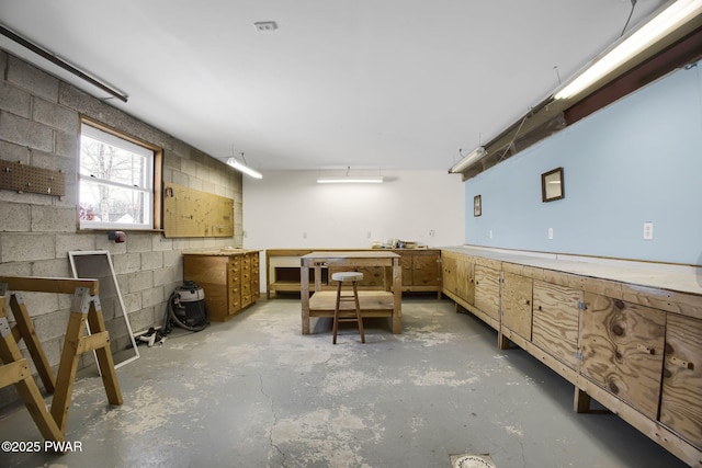 interior space featuring concrete block wall and unfinished concrete flooring