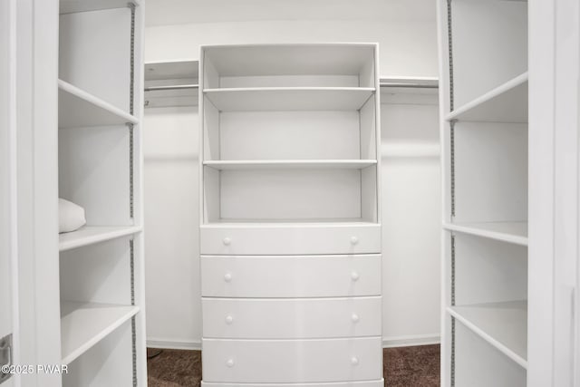 walk in closet featuring dark carpet